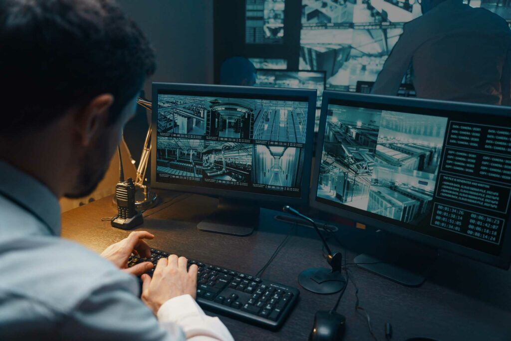 Security expert monitoring multiple surveillance screens in a dimly lit control room, ensuring safety and security.