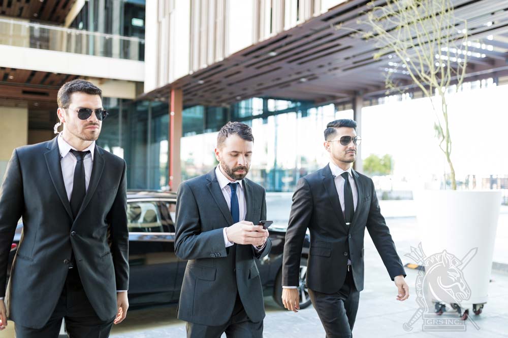 Three professional security guards on duty in a corporate setting, with the central guard focused on a smartphone..