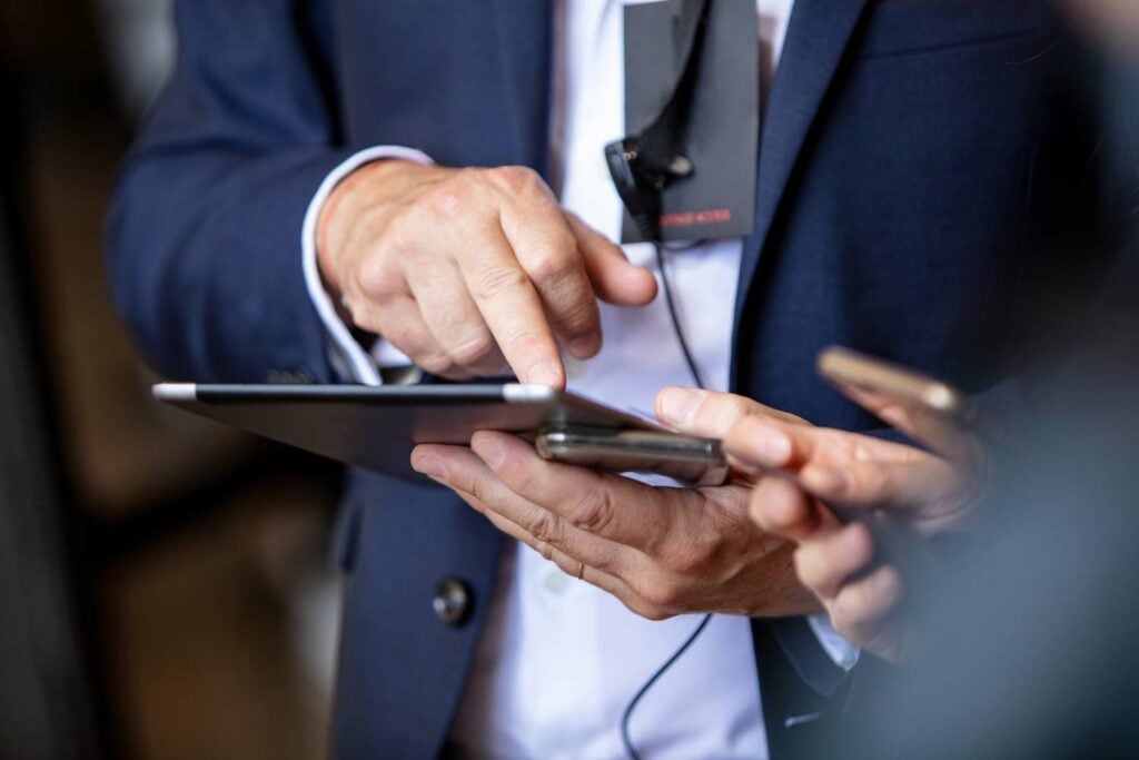 An executive protection agent performs a threat assessment on his tablet device as he determines the cost of a security guard