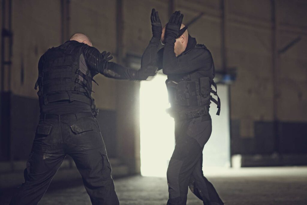 Two bodyguards practicing hand-to-hand combat in tactical gear during a training session.