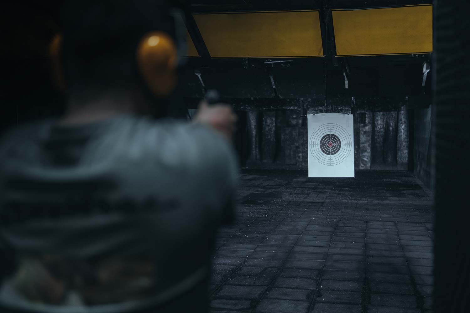 Person practicing at a shooting range aiming at a target.