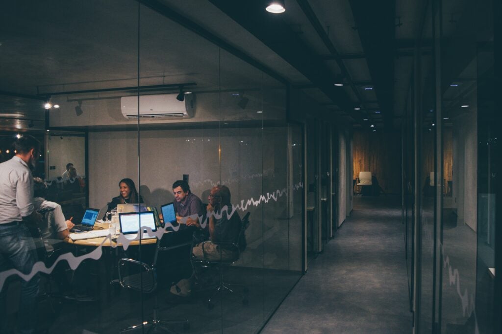 Team of professionals engaged in a meeting in a modern office with glass walls and ambient lighting.