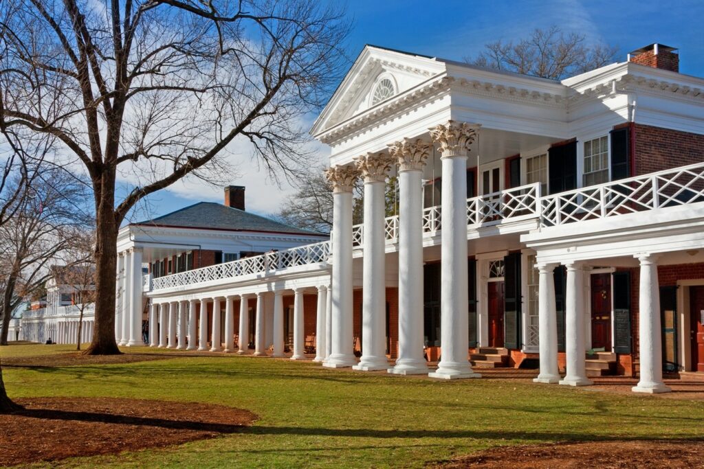 Historic colonial-style building with tall white columns and a brick facade on a clear day.