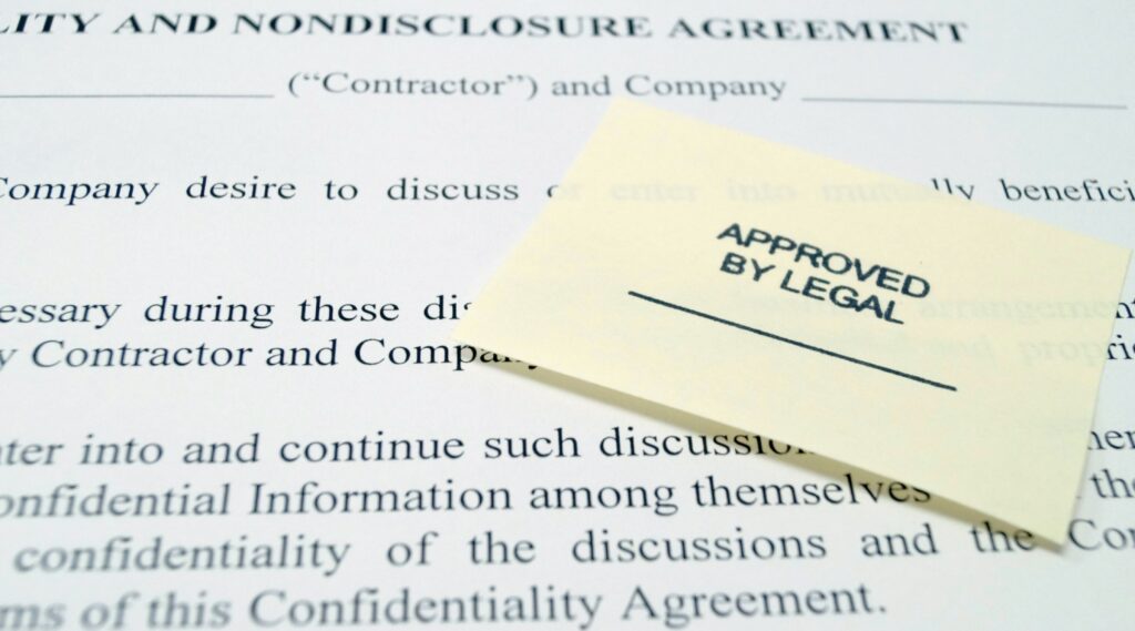 Close-up of a legal confidentiality and nondisclosure agreement with an "Approved by Legal" sticky note attached.