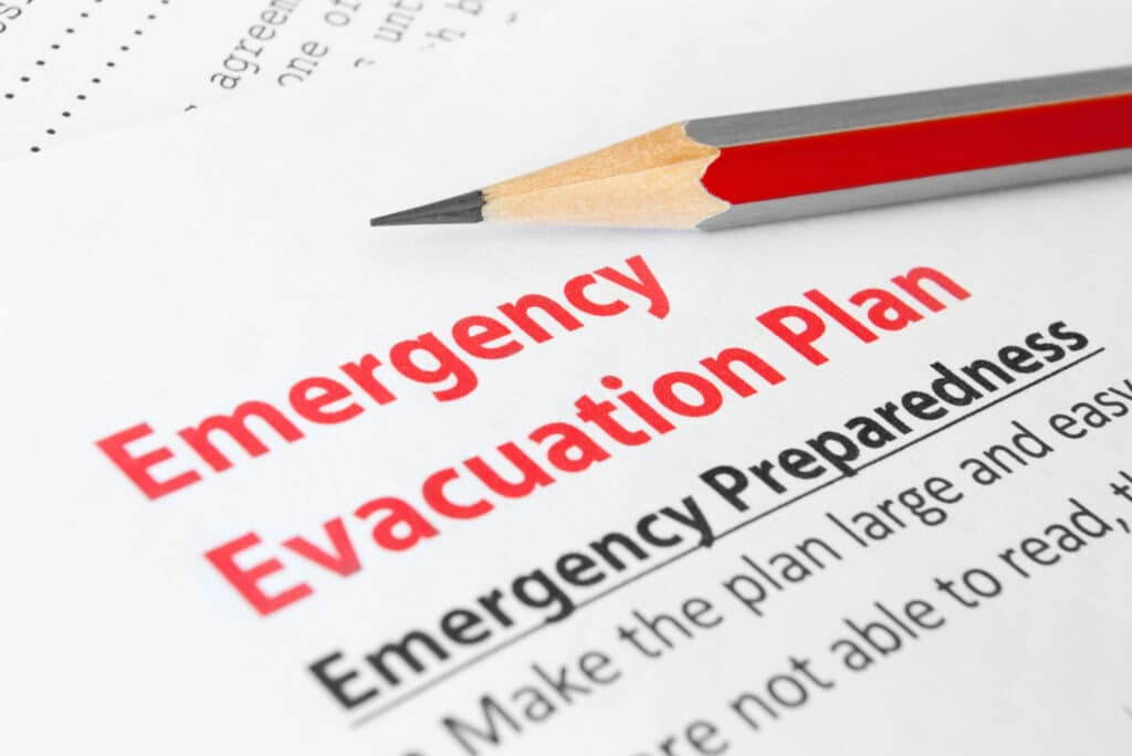 Close-up of an 'Emergency Evacuation Plan' document with a red and black pencil on top, emphasizing the importance of emergency preparedness
