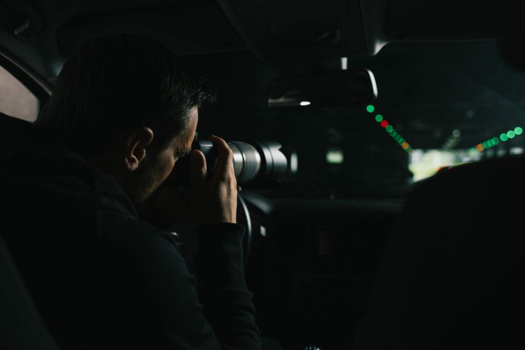 Photographer capturing images from inside a car at night, focused through a camera lens.
