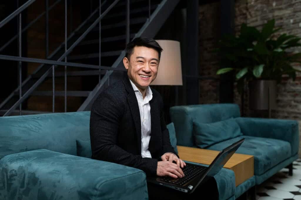 Businessman smiling while working on his laptop in a relaxed office environment, embodying the professional yet approachable ethos of Global Risk Solutions, Inc.