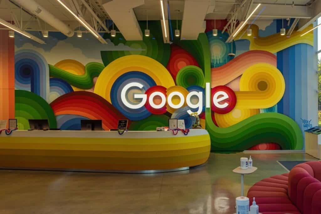 Colorful Google logo on a wall inside a modern office space.