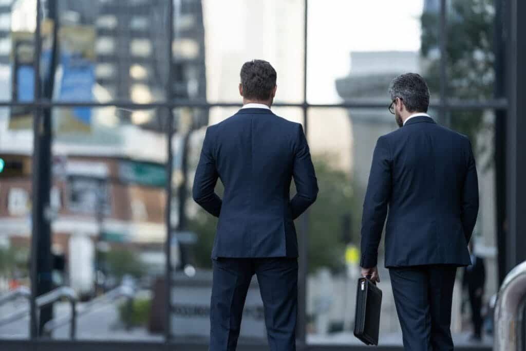 Rear view of two professionals in suits, one holding a briefcase, indicating a secure escort.