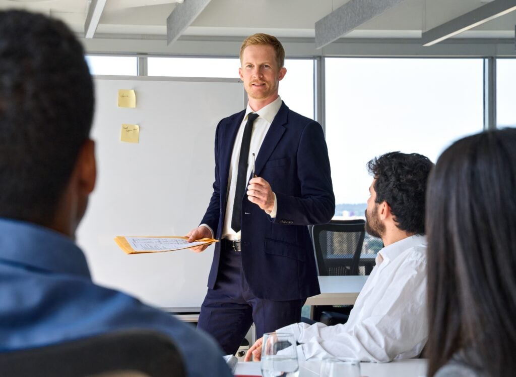 Global Risk Solutions expert leading a security strategy session with corporate clients, discussing risk management and protective measures in a well-lit conference room.