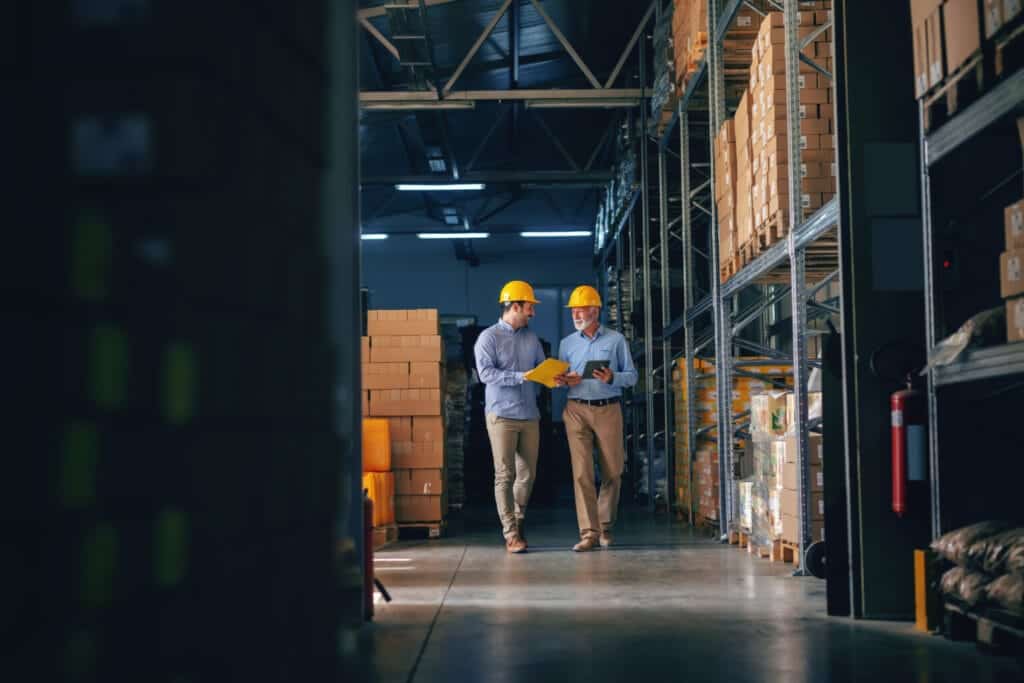 Two working men walking inside of a shipping factory