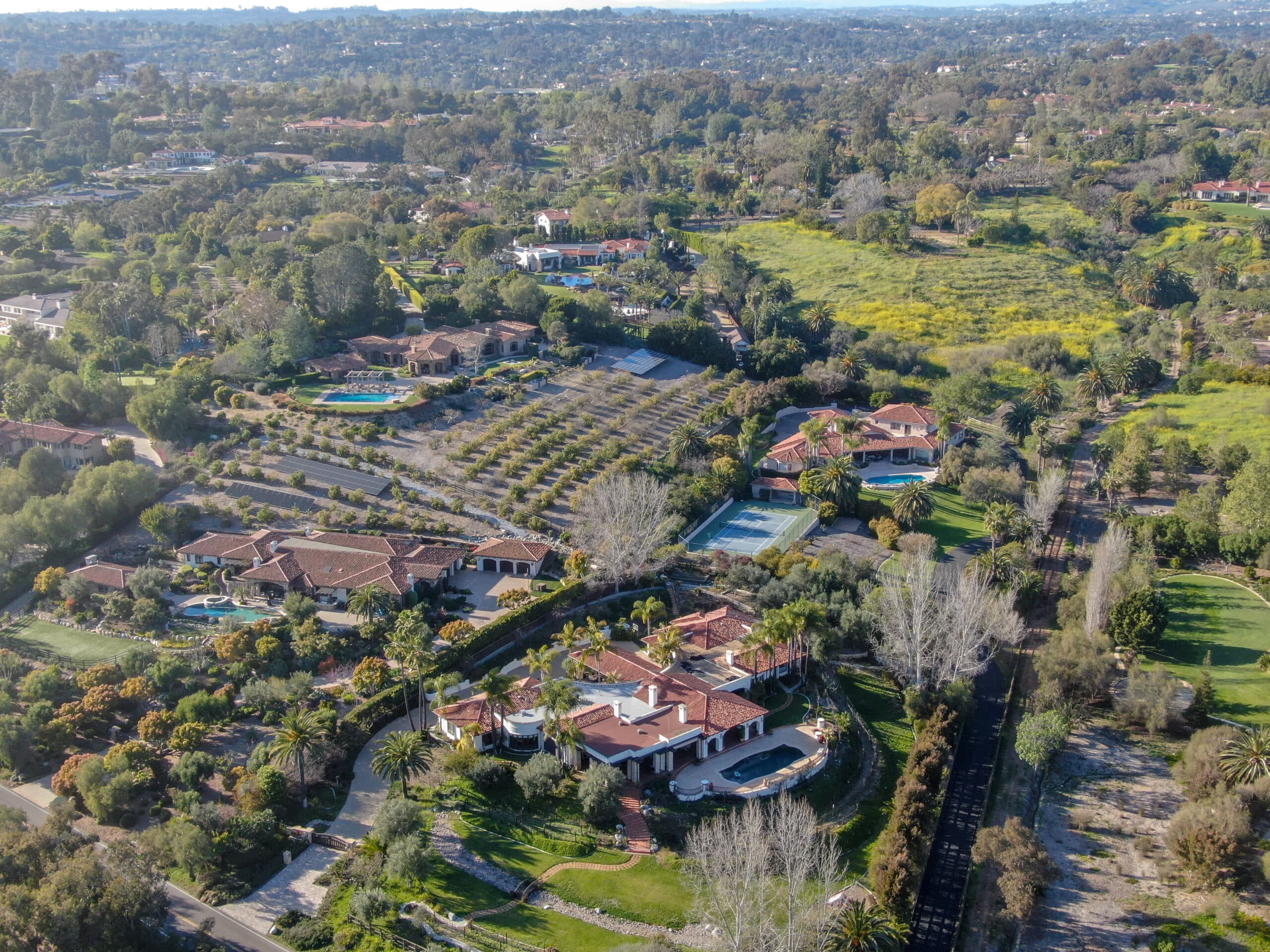 Aerial view of luxurious Rancho Santa Fe homes surrounded by lush greenery, highlighting the upscale residential area in California.