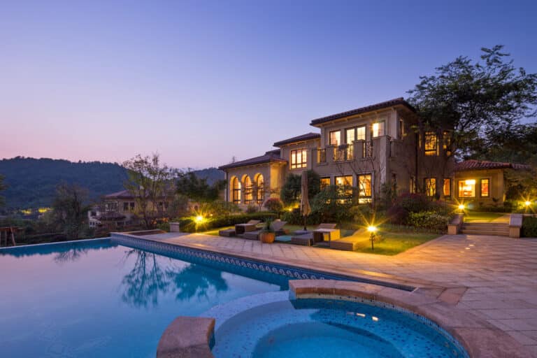 Twilight view of a luxury Atherton estate with illuminated landscaping, secured by Global Risk Solutions.