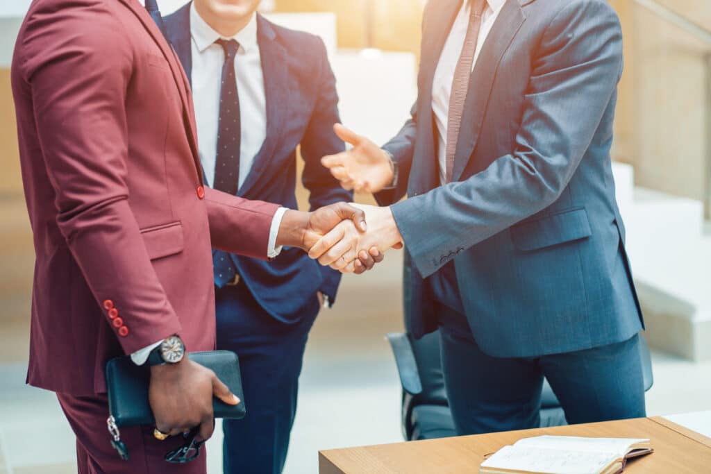 Two professionals in suits shaking hands in an office environment, symbolizing a secured partnership facilitated by Global Risk Solutions.
