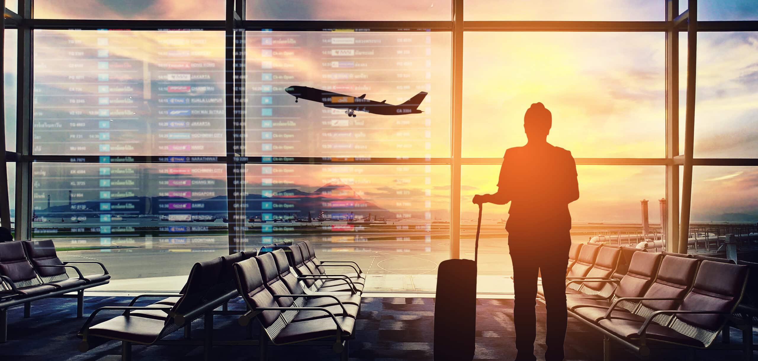Silhouette of a person standing at an airport window overlooking the runway, symbolizing Global Risk Solutions' commitment to secure and vigilant travel security services.