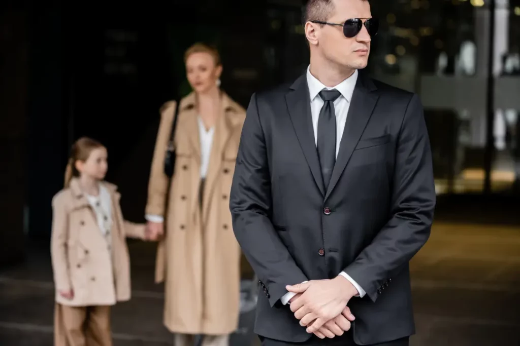 A professional security agent in a suit stands guard in front of a woman and child, showcasing advanced close protection services.