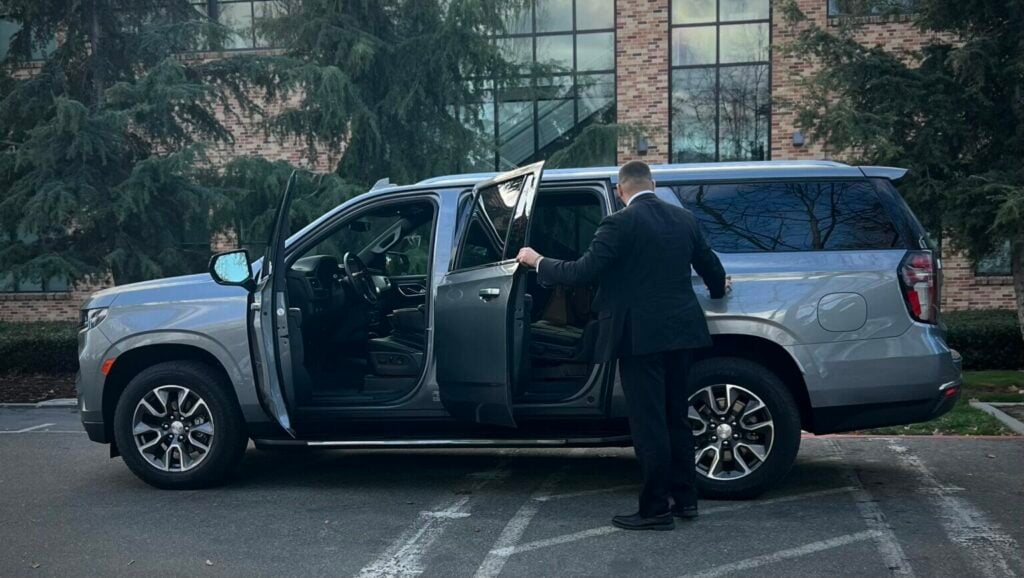 Essential Gear For Close Protection Agents: What The Pros Rely On 5 Security professional holding the door of a luxury SUV, showcasing essential gear for efficient and safe transportation.