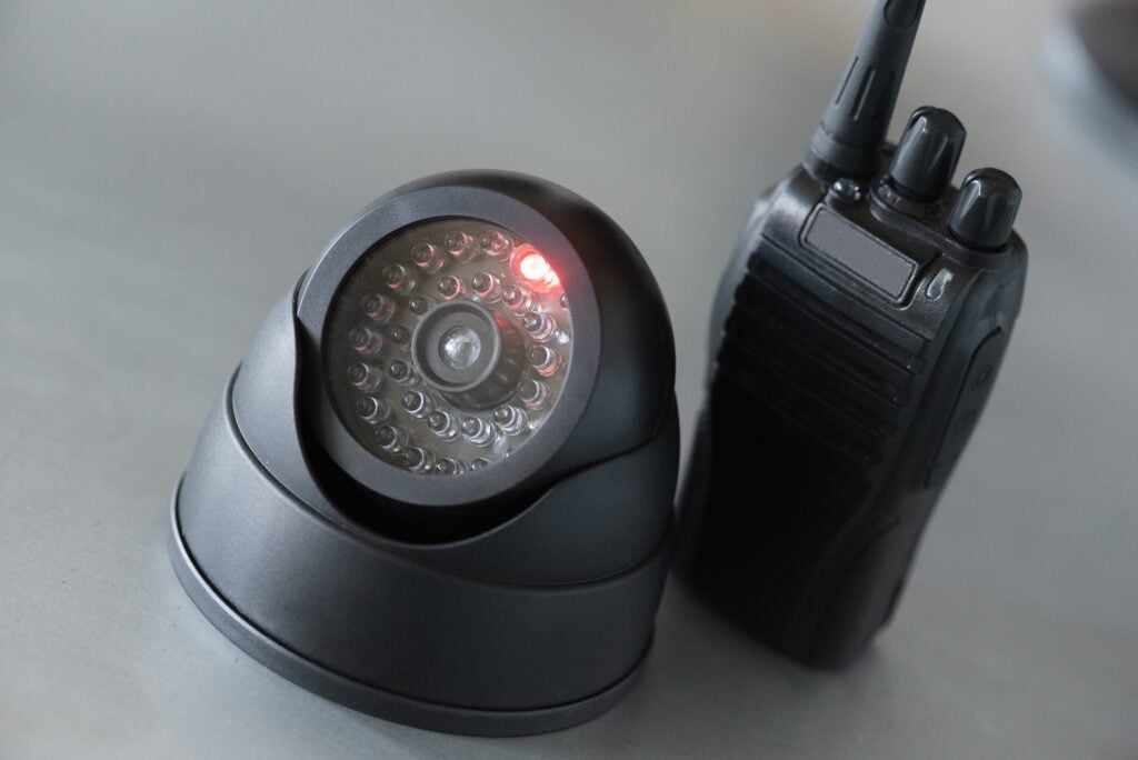 Essential gear for security operations, featuring a surveillance camera and a walkie-talkie radio on a table.