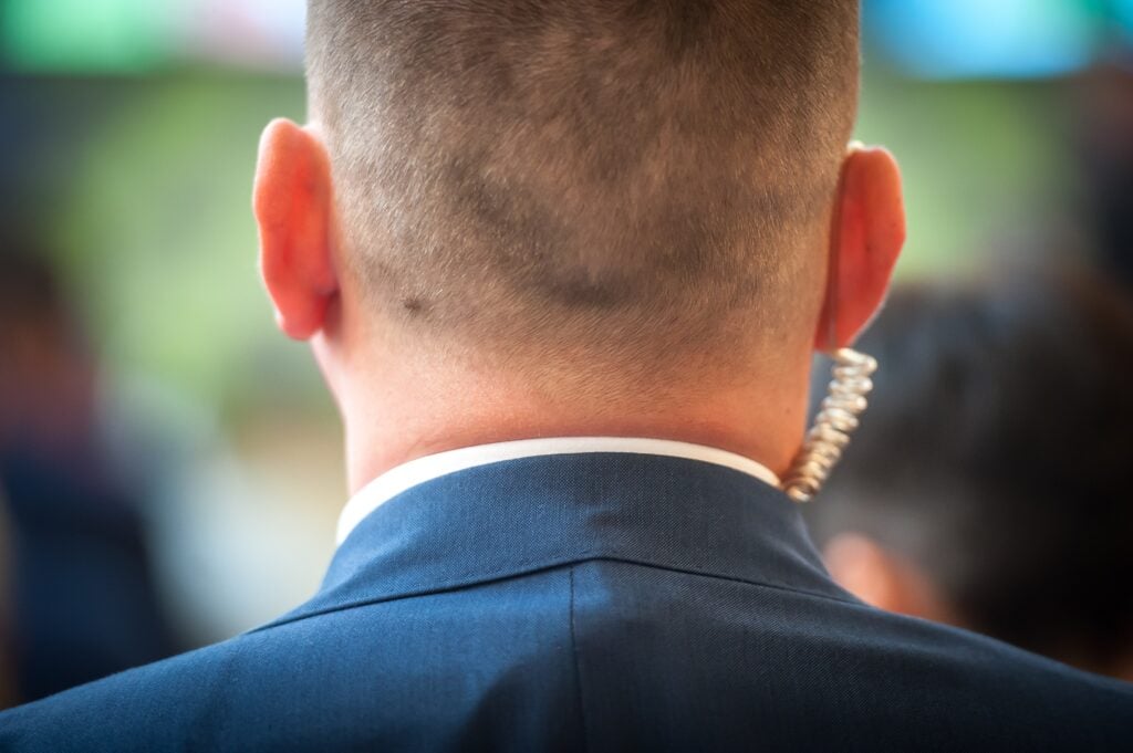 Close-up of a corporate security agent wearing a suit and earpiece, monitoring a secure event.