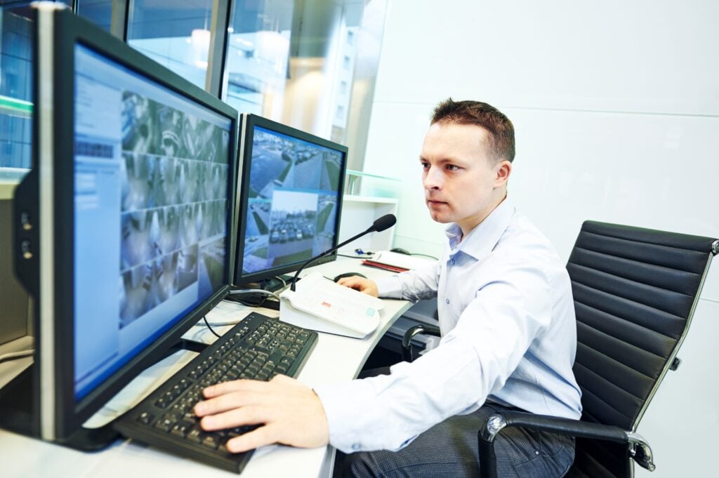 Innovations In Executive Protection: Technology'S Role In Modern Security 11 A security officer monitoring multiple surveillance screens, showcasing the role of Technology in Executive Protection.