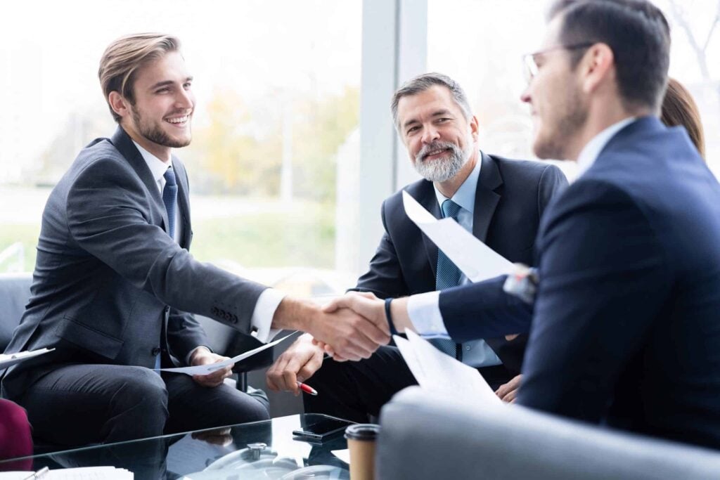 The Psychology Of Executive Protection: Building Trust And Managing Expectations 4 Business professionals engage in a handshake during a meeting, highlighting the role of trust and discretion in executive protection.