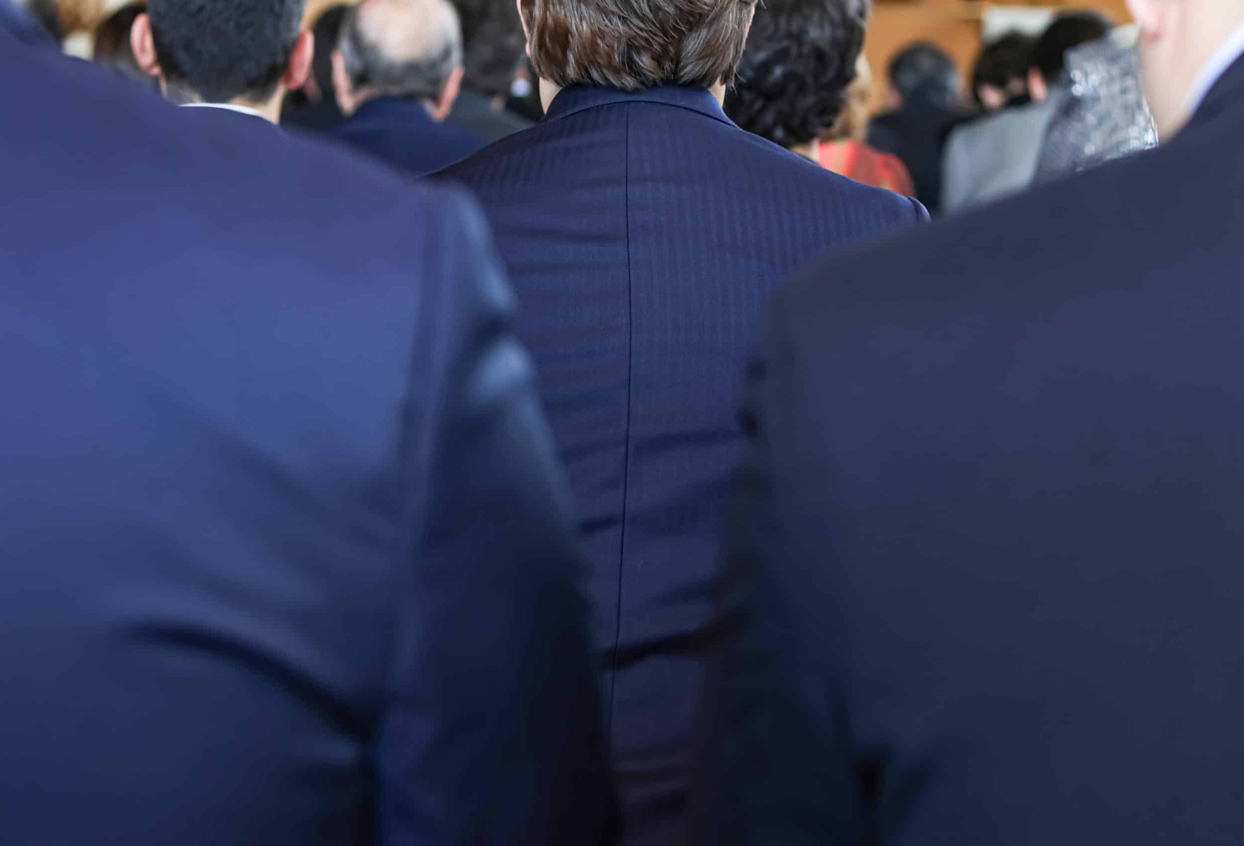 Back view of suited professionals in a gathering, illustrating the discreet presence of an event security team in action.