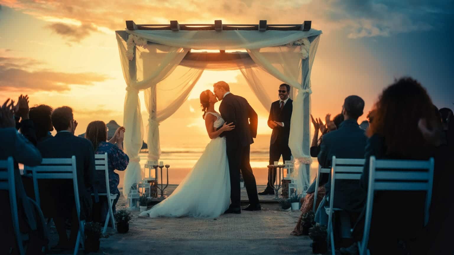 Couple kissing at sunset beach ceremony protected by destination wedding security team