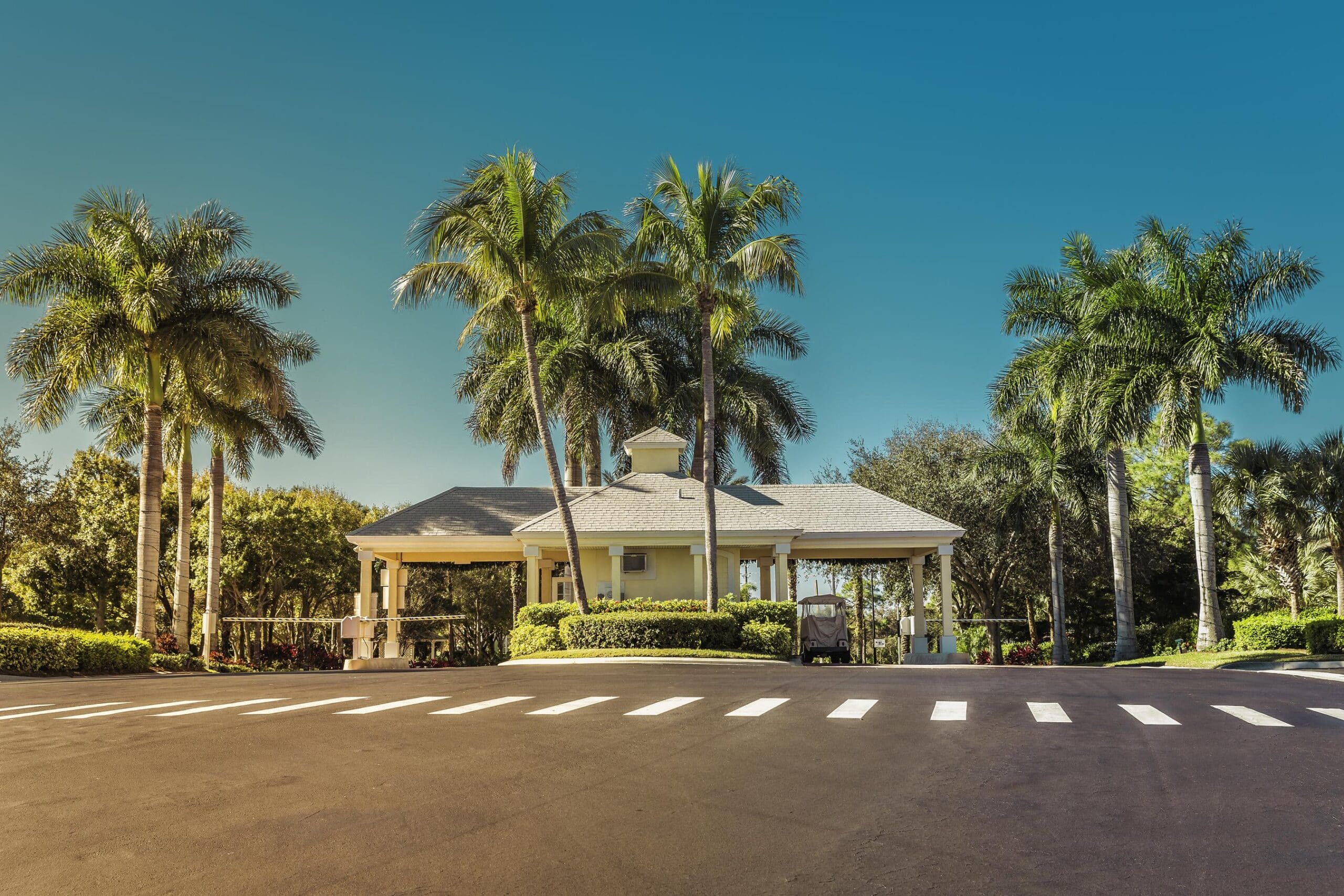 Luxury gated community entrance gate with guardhouse and palm trees showing private security for gated communities checkpoint